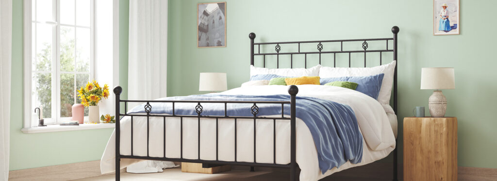 Victorian Iron Bed with pastel green walls and blue throw